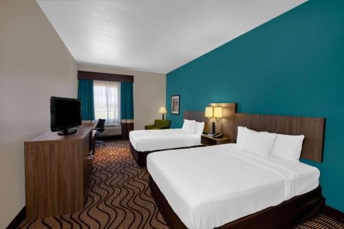 um quarto de hotel com duas camas e uma televisão de ecrã plano em La Quinta by Wyndham Midland North em Midland