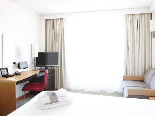 a hotel room with a bedroom with a desk and a bed at Novotel Lille Centre Gares in Lille