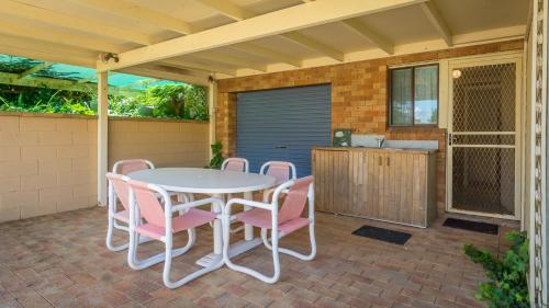 a patio with a white table and pink chairs at By The Sea, Culburra Beach in Culburra Beach