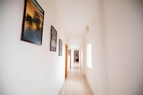 a hallway with white walls and pictures on the walls at Golden Bee Hotel in Da Lat