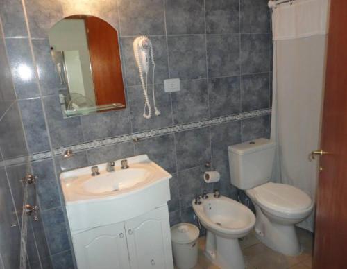 W łazience znajduje się umywalka, toaleta i lustro. w obiekcie Médanos Hotel w mieście San Clemente del Tuyú