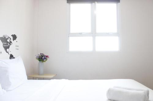 a white bedroom with a white bed and a window at Spacious and Well Appointed 2BR @ Gateway Pasteur Apartment By Travelio in Bandung