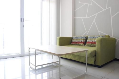 a living room with a green couch and a table at Spacious and Well Appointed 2BR @ Gateway Pasteur Apartment By Travelio in Bandung