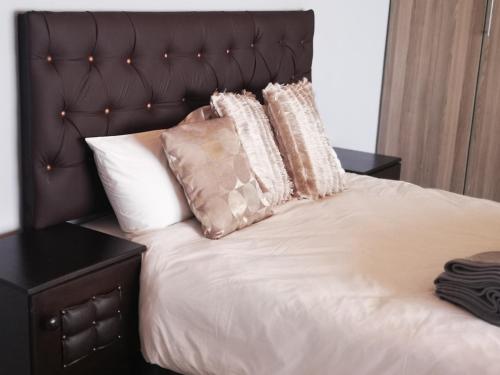 ein Bett mit weißer Bettwäsche und Kissen darauf in der Unterkunft Tuvawa Luxury Suites in Walvis Bay