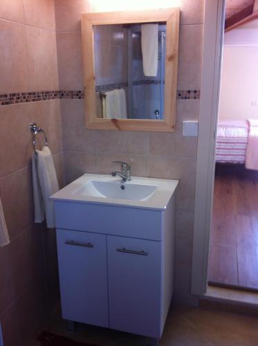 uma casa de banho com um lavatório branco e um espelho. em Off The Square em Safed