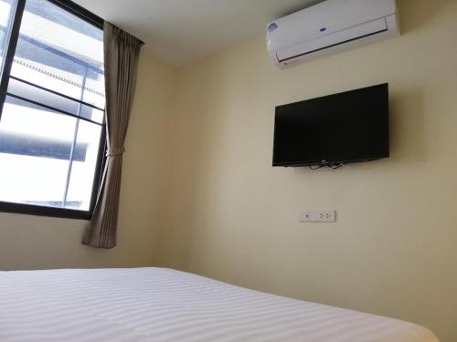 um quarto com uma cama e uma televisão de ecrã plano na parede em The Marble Hostel em Banguecoque