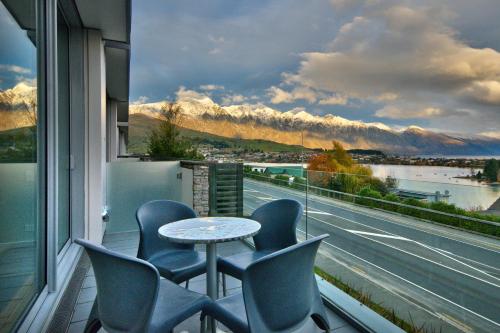 a balcony with chairs and a table and a window at Hello QT Pounamu in Queenstown