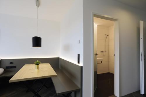 Habitación con mesa y baño con ducha. en Saminapark Aparthotel en Frastanz