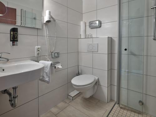 La salle de bains blanche est pourvue de toilettes et d'un lavabo. dans l'établissement Hotel Gasthaus zur Linde, à Seevetal