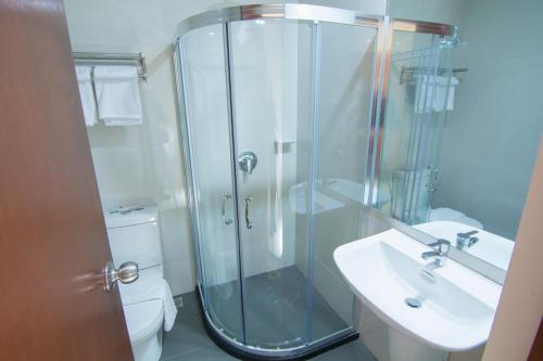 a bathroom with a glass shower and a sink at Mango Suites Cauayan in Cauayan City