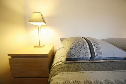d'un lit avec une table de nuit et une lampe. dans l'établissement Appartement tout confort au pied du Métro Glacière, à Paris