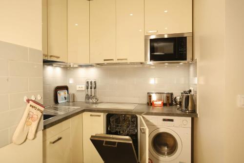 une cuisine avec un lave-linge et un micro-ondes dans l'établissement Charmante Santé, à Paris