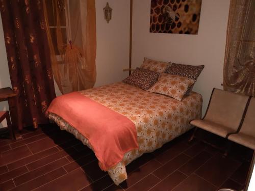 a small bedroom with a bed and a chair at LA BELLE D'ANTAN in Saint-Bonnet-en-Bresse