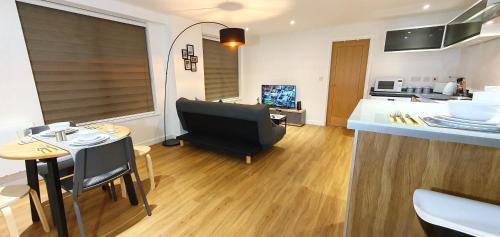 a living room with a couch and a table and a kitchen at Northampton 2 Bedroom Town Centre Apartment close to University, Hospitals, Brackmills in Northampton