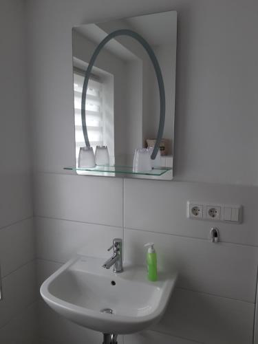 a white bathroom with a sink and a mirror at Zur alten Sommerküche in Markische Heide