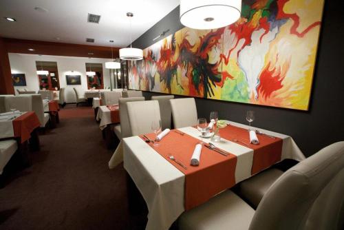 a restaurant with tables and chairs and a painting on the wall at Hotel Peklo in Komárno