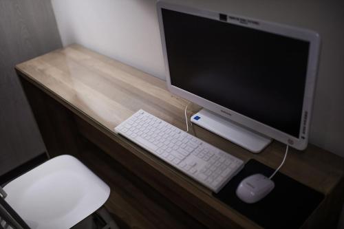 a desk with a computer monitor and a keyboard and mouse at Soho Hotel Airport in Daegu