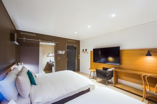 a hotel room with a bed and a flat screen tv at Soho Hotel Airport in Daegu