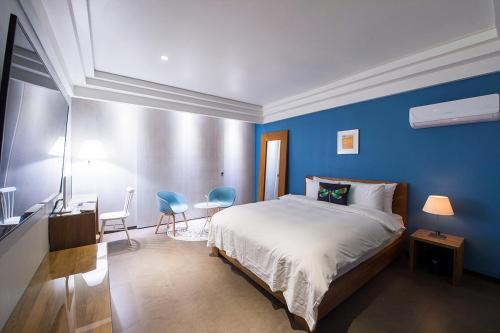 a blue bedroom with a bed and a table and chairs at Soho Hotel Airport in Daegu