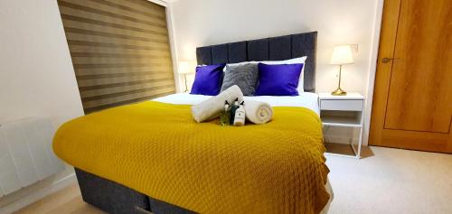 a bedroom with a yellow bed with two stuffed animals on it at Northampton 2 Bedroom Town Centre Apartment close to University, Hospitals, Brackmills in Northampton