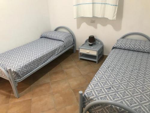 2 Einzelbetten in einem Zimmer mit einem Tisch in der Unterkunft La Rosa Dei Venti in Olbia