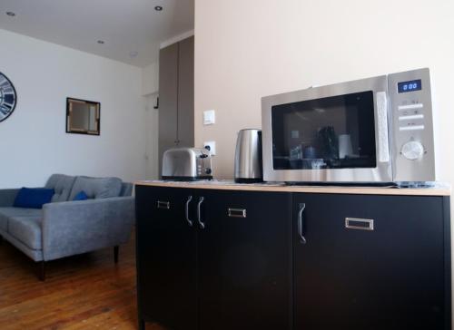 - un four micro-ondes au-dessus d'une armoire noire dans le salon dans l'établissement T2 de charme N3 Valenciennes Netflix, Wifi,, à Aulnoy