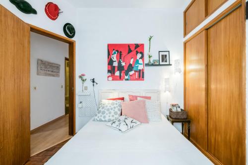 a bedroom with a white bed with a wooden door at Sons do Mar - Charming Apartment by the Sea in Armação de Pêra