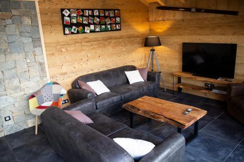 a living room with a couch and a television at Chalet Horizon 180 4 étoiles Sauna in Gérardmer
