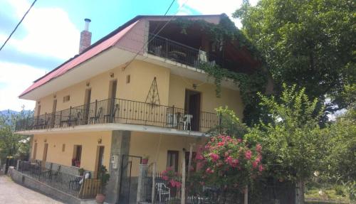 a large yellow house with a balcony at Guesthouse Chotos in Samarína
