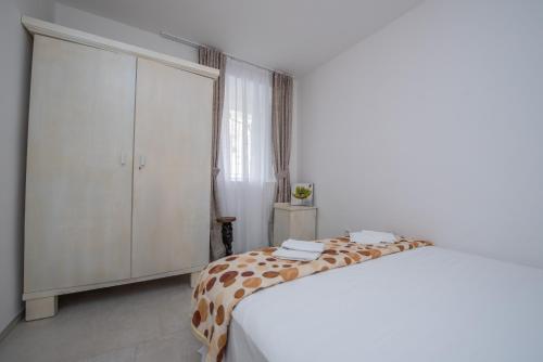 a white bedroom with a bed and a dresser at Apartment Kula Đurišić in Perast