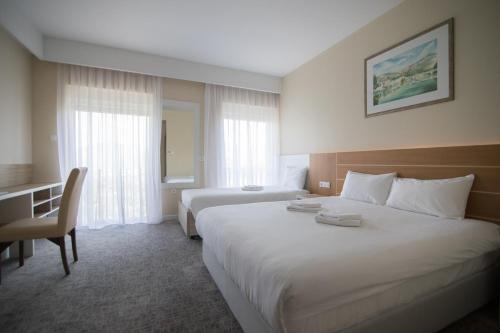 a hotel room with two beds and a desk at Hotel Bellevue in Trebinje