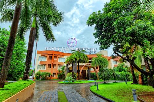 a hotel with palm trees in front of it at Flora Airport Hotel and Convention Centre Kochi in Nedumbassery