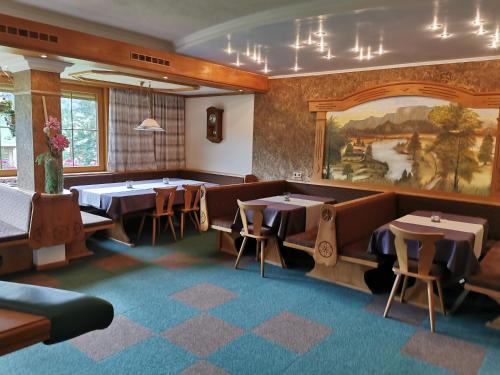 a restaurant with tables and chairs and a painting on the wall at Pension Elisabeth in Sankt Jakob in Haus