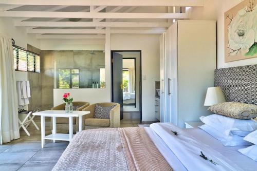 a bedroom with a bed and a table and a chair at Dreamhouse Guest House in Hout Bay