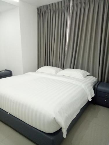 a bed with white sheets and pillows in front of a window at Chequers Suites Subic Bay in Olongapo