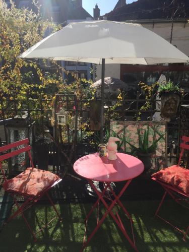 a pink table and two chairs with an umbrella at B&B Con Ampère in Bruges