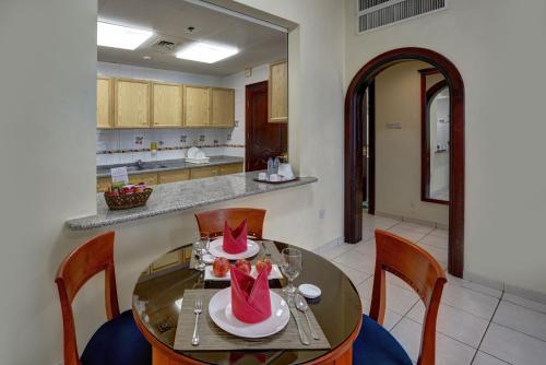 a dining room with a table and chairs and a kitchen at Al Nakheel Hotel Apartments Abu Dhabi in Abu Dhabi