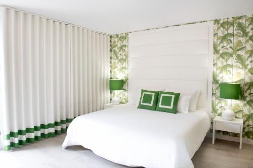 Hotel Cristal Praia Resort & SPA في برايا دا فييرا: غرفة نوم بيضاء مع سرير أبيض مع لهجات خضراء