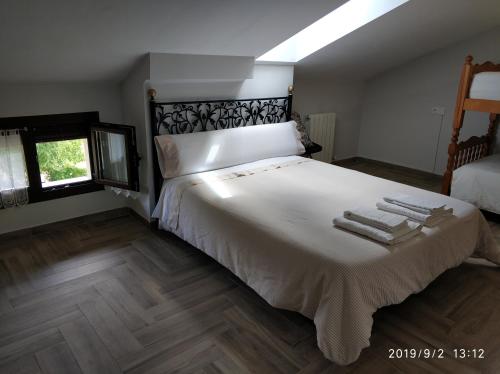 1 dormitorio con 1 cama grande con sábanas blancas y suelo de madera en Casa Rural Torres, en Valdenoceda