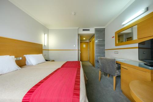 um quarto de hotel com uma cama grande e um cobertor vermelho em Hotel Santo Amaro - SA Hotels em Fátima