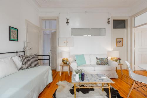 een woonkamer met een witte bank en een tafel bij Spacious, Bright and Sunny Apartment, By TimeCooler in Lissabon