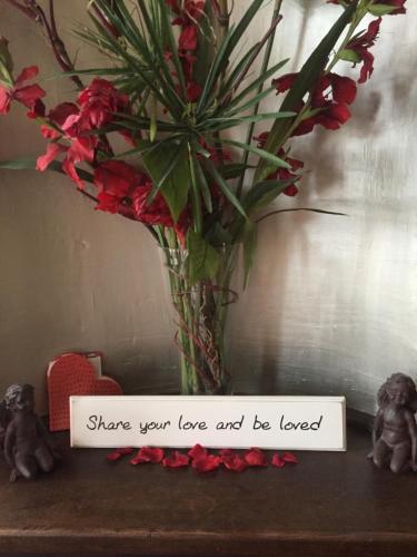 a vase with flowers and a sign that says share your love and be loved at B&B Con Ampère in Bruges
