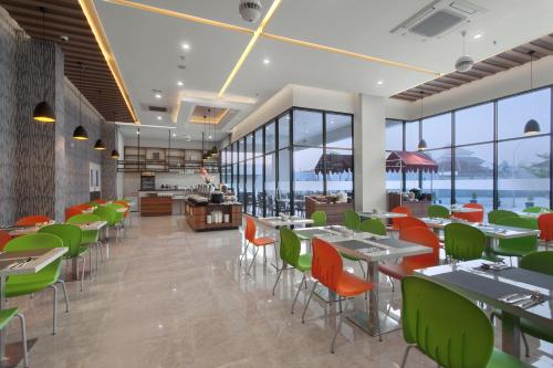 a restaurant with tables and chairs and windows at favehotel Hasyim Ashari Tangerang in Tangerang
