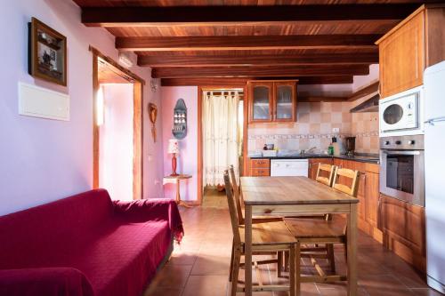 une cuisine avec une table en bois et un canapé rouge dans l'établissement Home2Book Stunning Rustic House El Pinar & WiFi, à El Pinar del Hierro