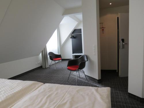 a hotel room with two chairs and a bed at Comfor Hotel Ulm City in Ulm