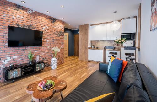 - un salon avec un canapé et un mur en briques dans l'établissement Apartament Merkury z parkingiem, à Toruń