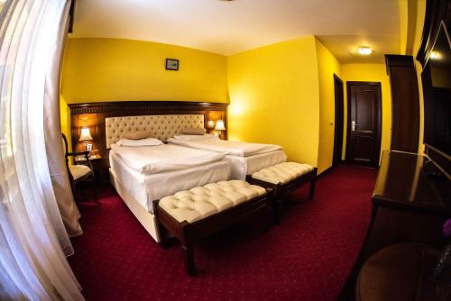 a hotel room with a large bed and two chairs at Hotel Trei Brazi in Băile Olăneşti