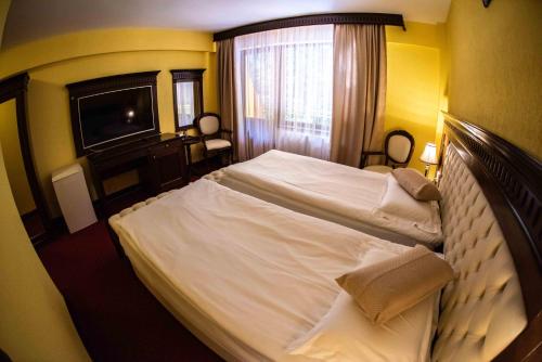 a bedroom with a large white bed in a room at Hotel Trei Brazi in Băile Olăneşti