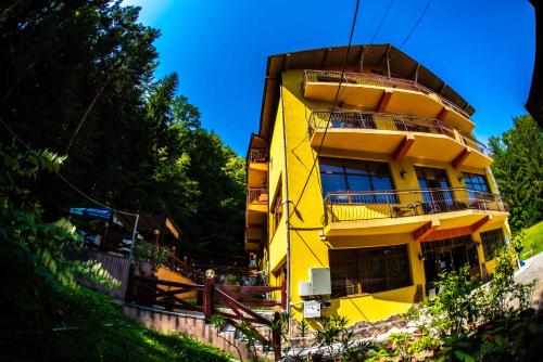 a yellow building with balconies on the side of it at Hotel Trei Brazi in Băile Olăneşti