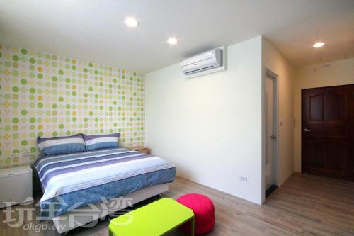 una camera con letto e sgabello verde di Aqua Night Market Homestay a Luodong